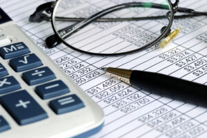 Commercial Litigation Attorney New York, NY with a calculator, glasses, pen, and spreadsheet