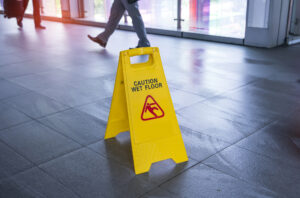 Premises Liability Attorney New York, NY with a wet floor sign with a man walking in the background